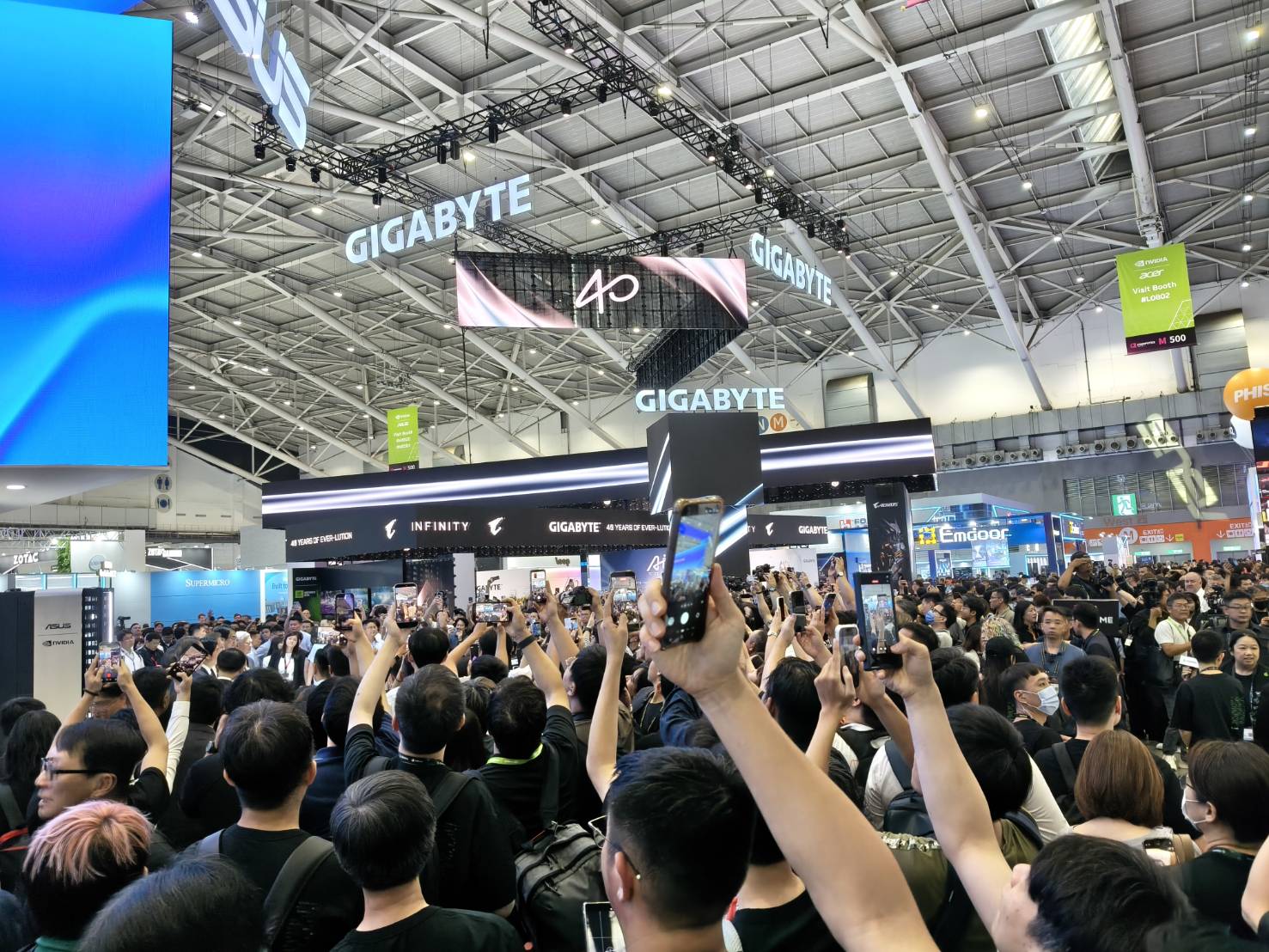 COMPUTEX 2026 展位設計，南港展覽館一館四樓人潮中各品牌靠頭頂懸吊量體爭取垂直視野